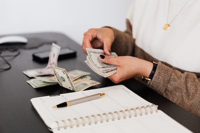 person with notebook counting money